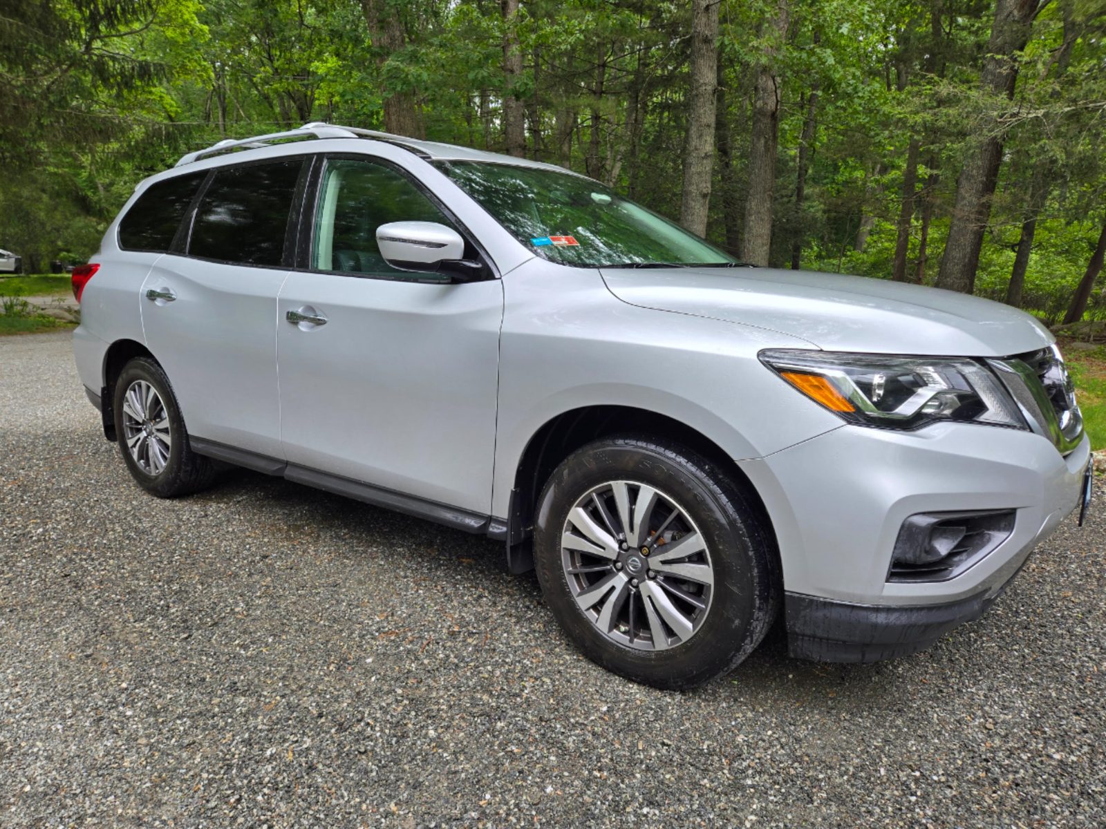 EG Medlink courier vehicle, a silver SUV parked on a wooded gravel driveway